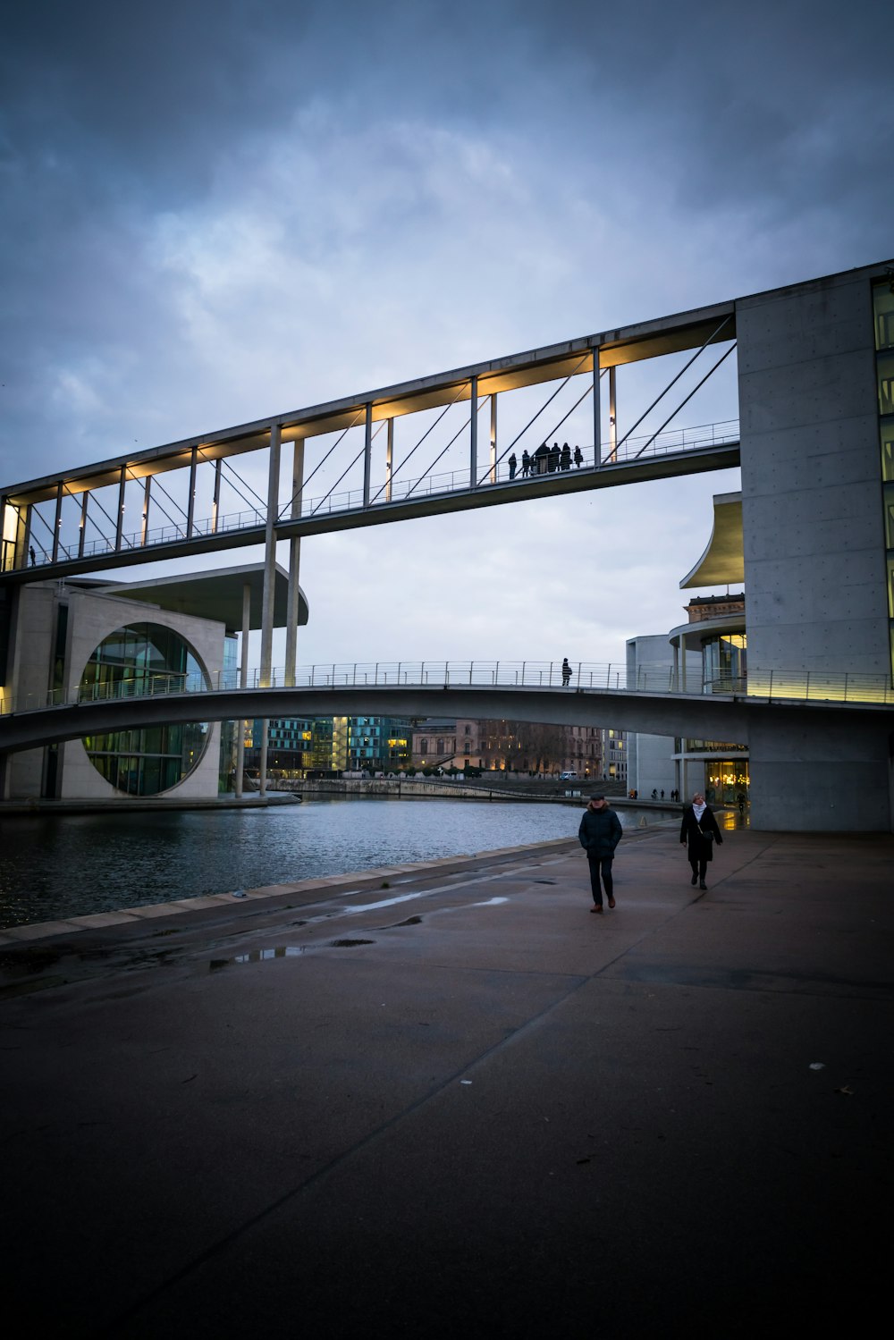 people walking on gray concrete bridge under gray cloudy sky during daytime