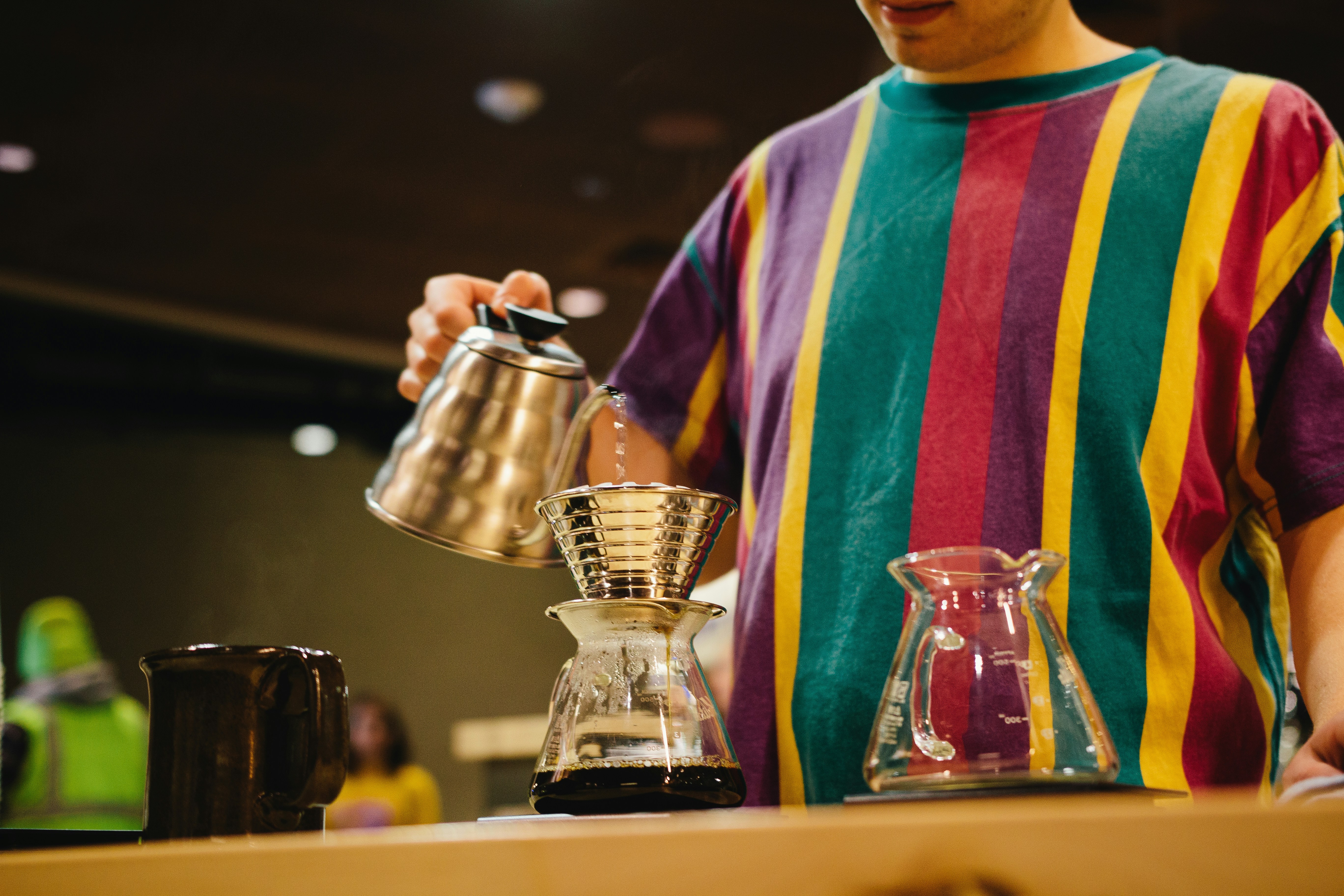 Man in a striped shirt brewing pour-over coffee