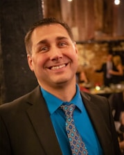 Portrait of Dato Marcus Mehta in a dark blue suit, confidently smiling against a gold-accented backdrop.