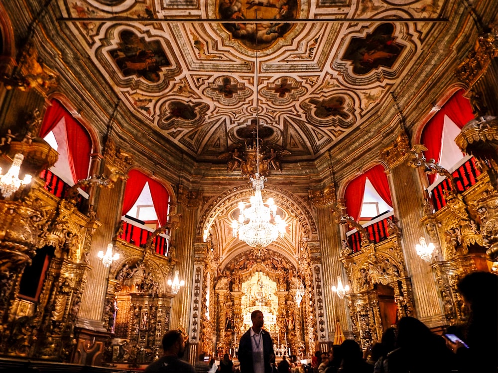 people inside cathedral with red and gold ceiling