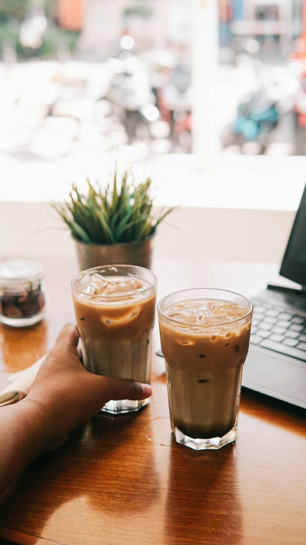 person holding clear drinking glass with brown liquid