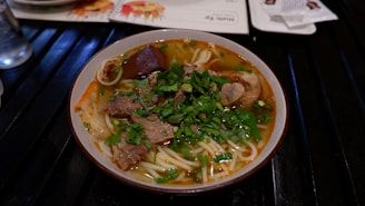 A vibrant bowl of traditional Vietnamese pho with fresh herbs.