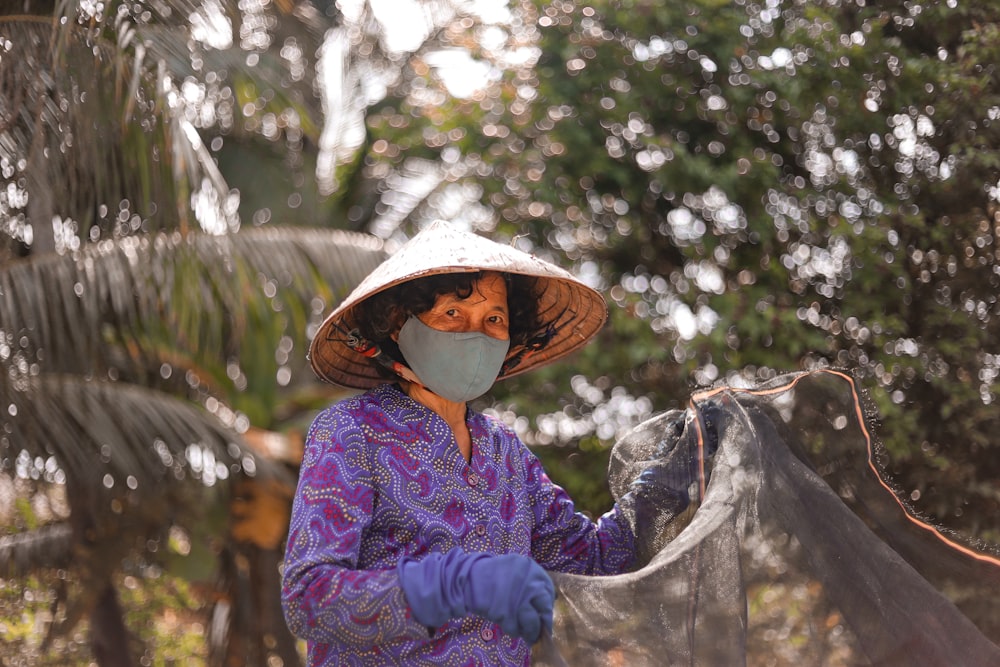 Femme en chemise à manches longues violette et blanche portant un chapeau de paille marron