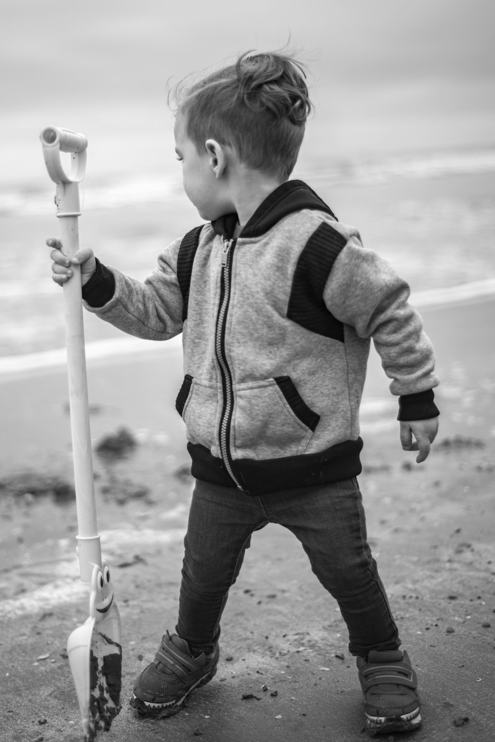boy in gray and black hoodie holding white stick