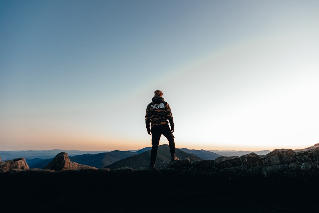 man in black jacket standing on top of mountain during daytime