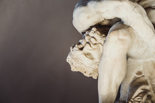 A marble statue depicting a muscular figure in a dynamic, twisting pose. The detailed facial expression and robust physique suggest classical influences. The texture of the stone is smooth and polished, showcasing expert craftsmanship.