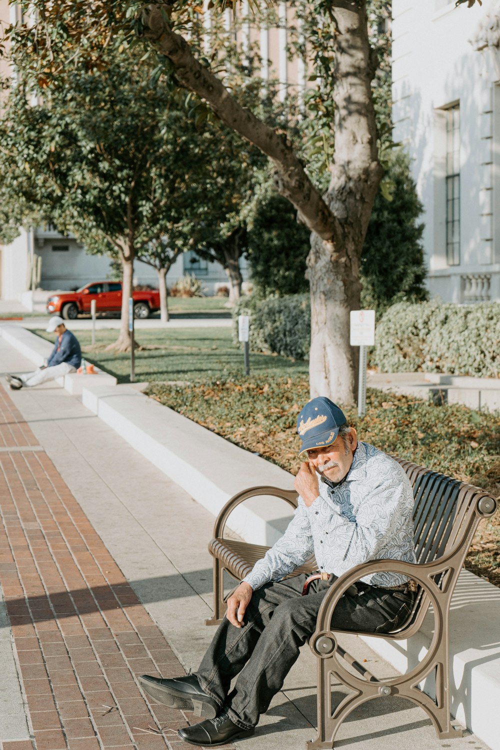 man in purple shirt sitting on brown wooden bench