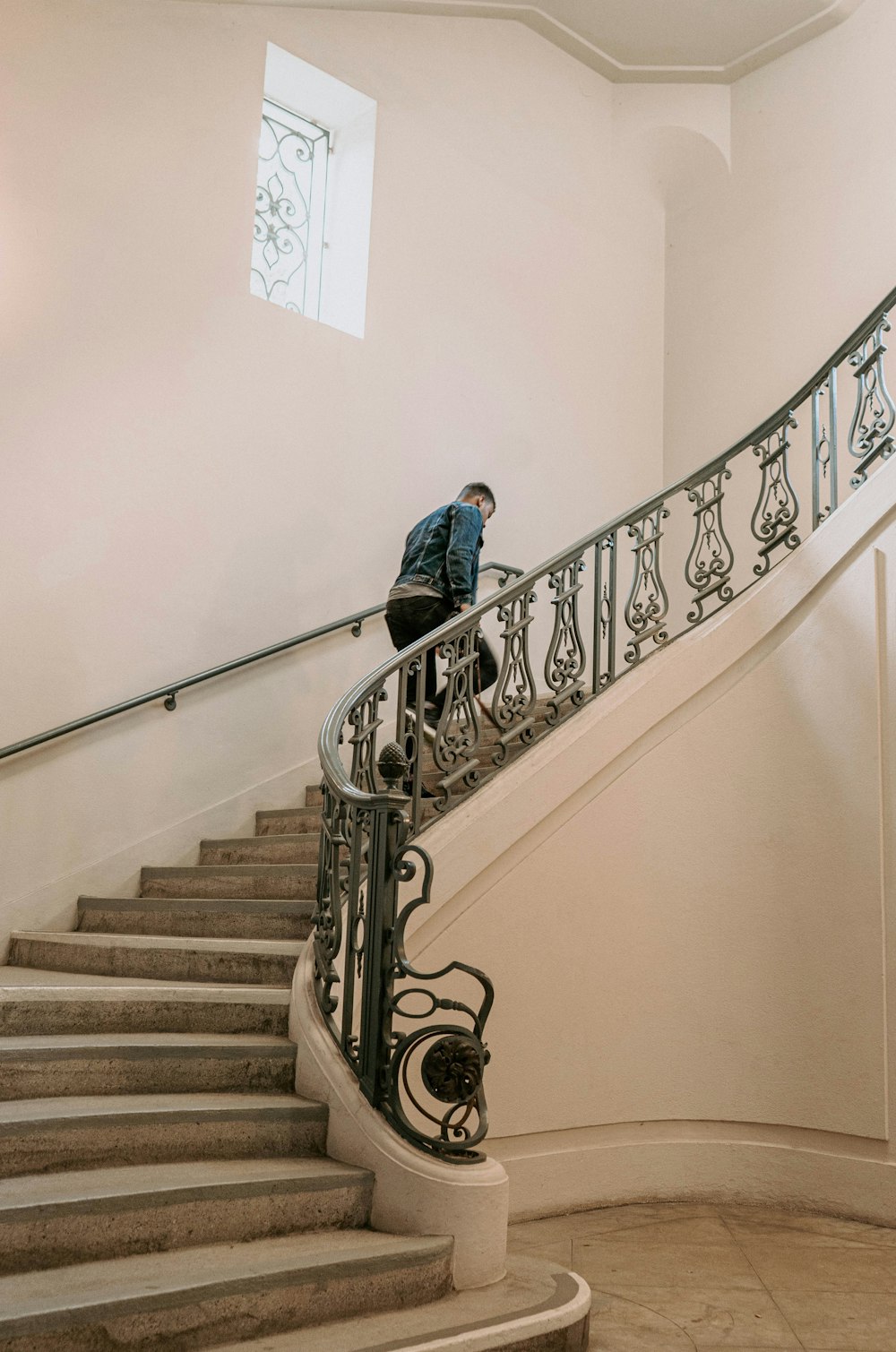 woman in blue long sleeve shirt and blue denim jeans walking down on staircase