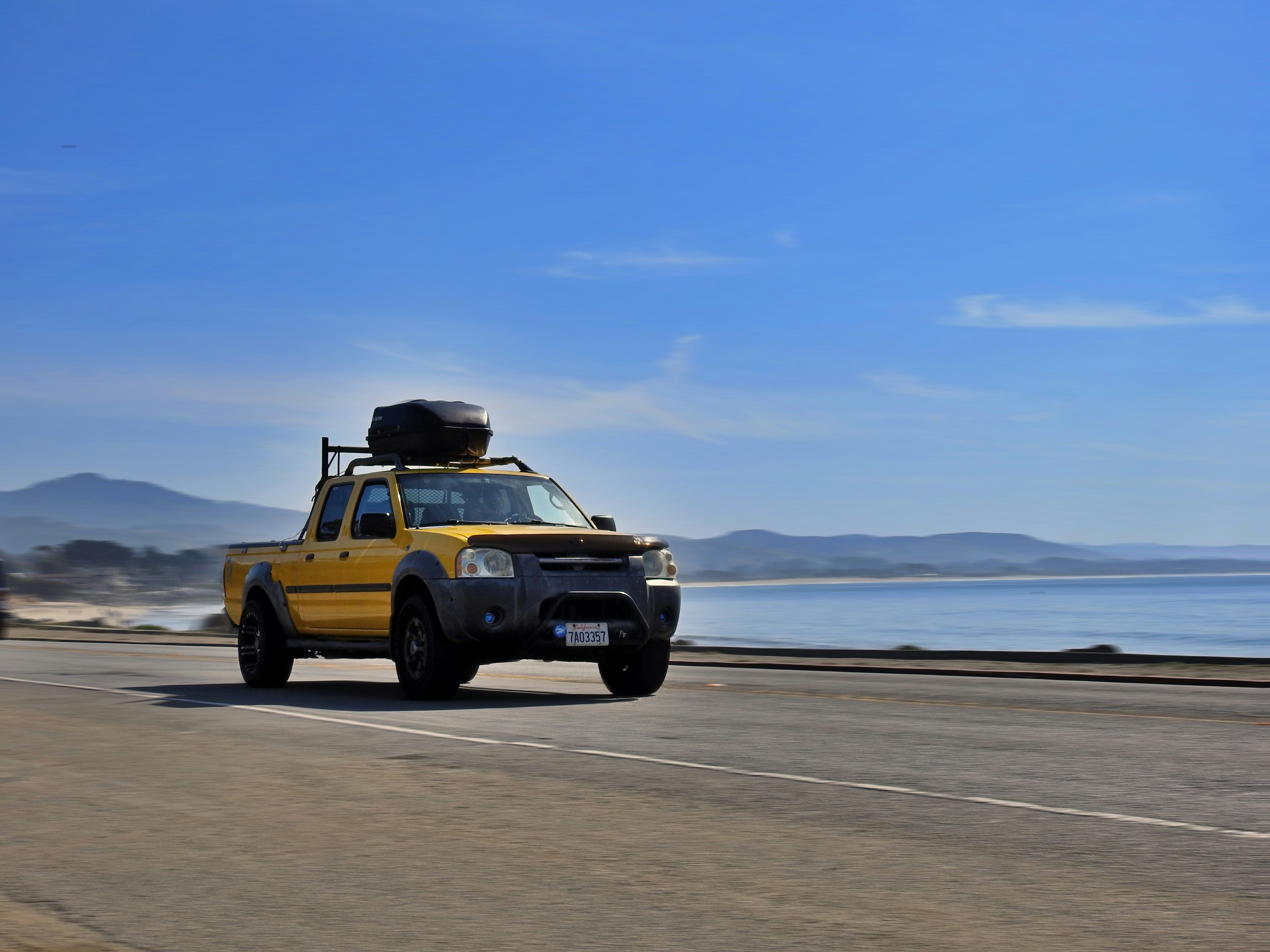 yellow and black jeep wrangler on gray sand under white clouds during daytime