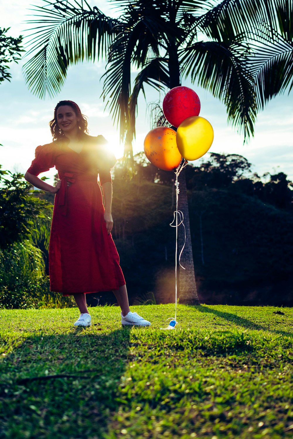 Femme en robe rouge tenant des ballons jaunes