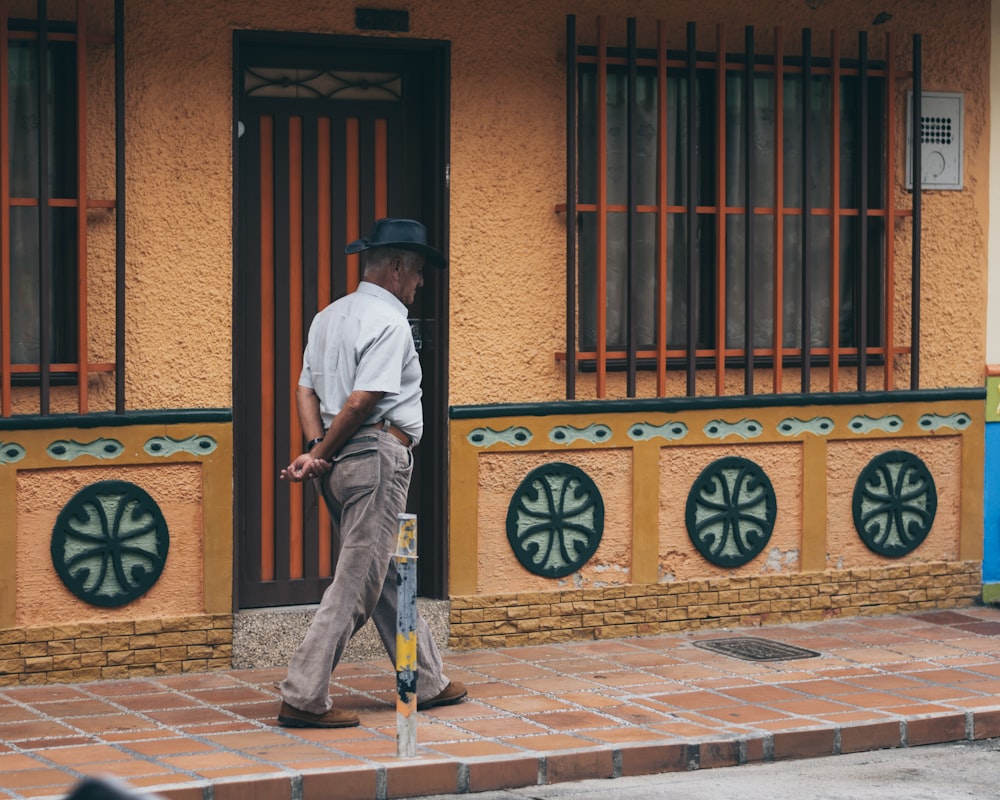 man in white dress shirt and gray pants walking on sidewalk during daytime