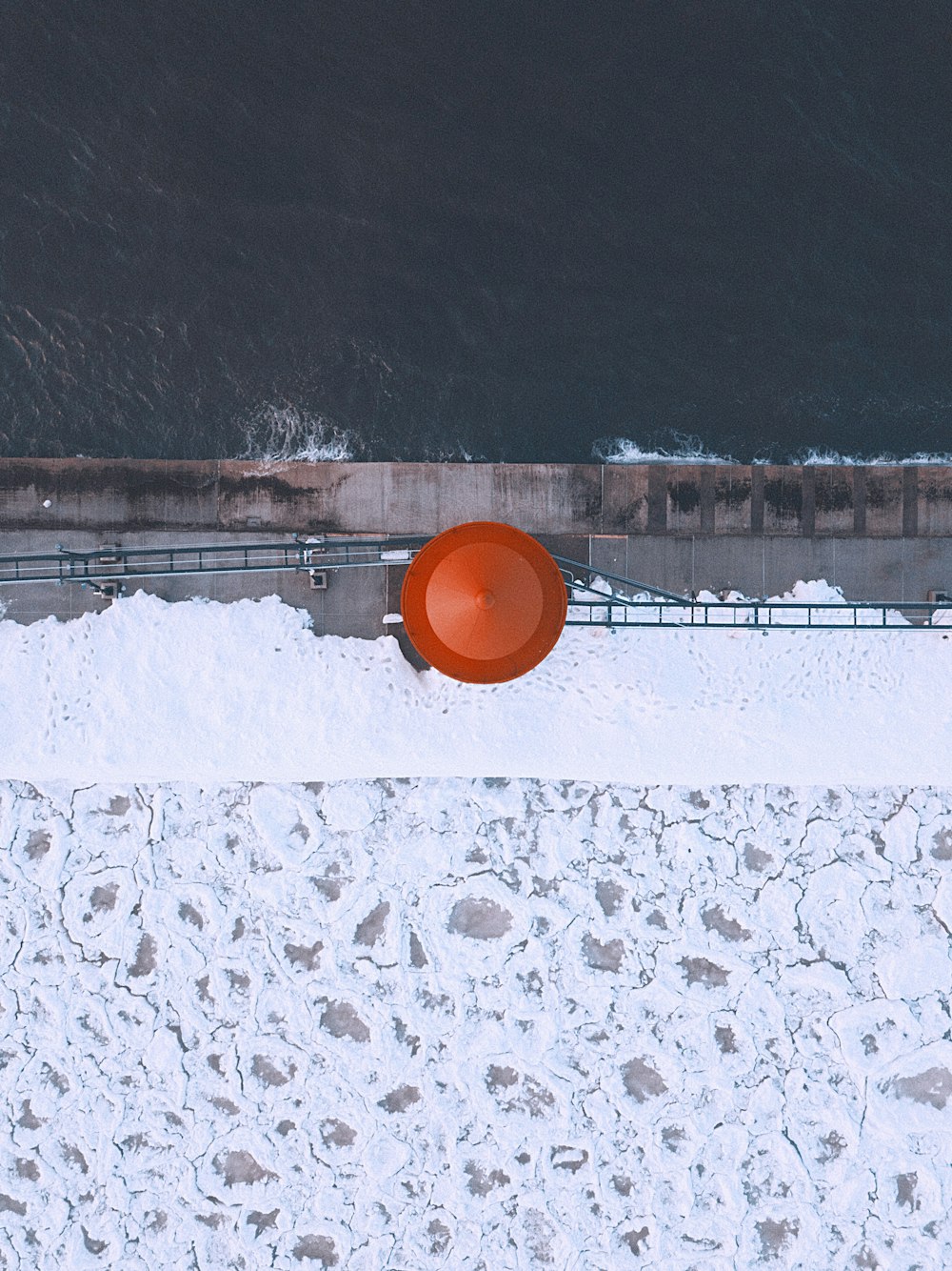雪に覆われた地面の上に座っている大きなオレンジ色のフリスビー