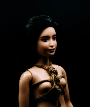 A doll with dark hair tied with rope