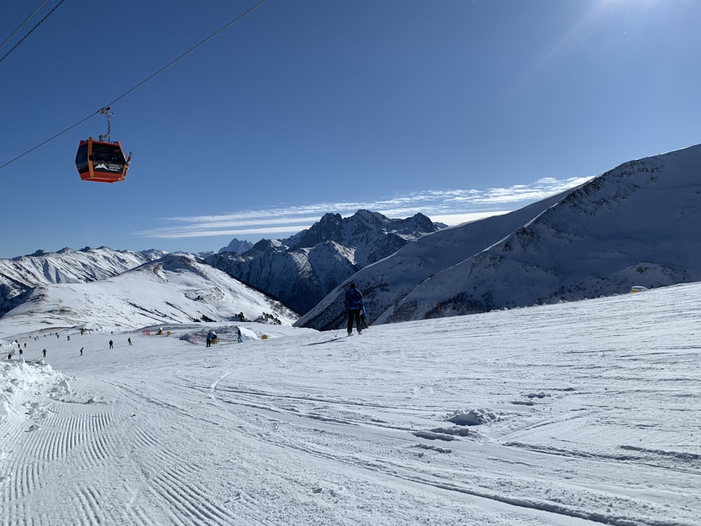 orange cable car over snow covered mountain during daytime