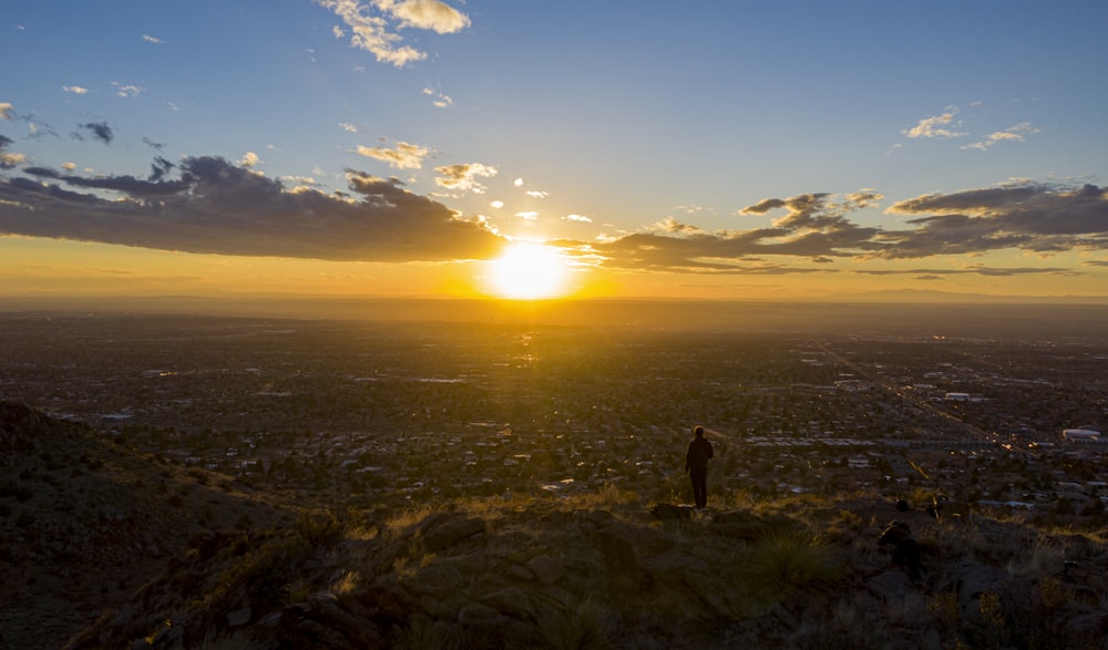 silhouette of 2 person standing on mountain during sunset