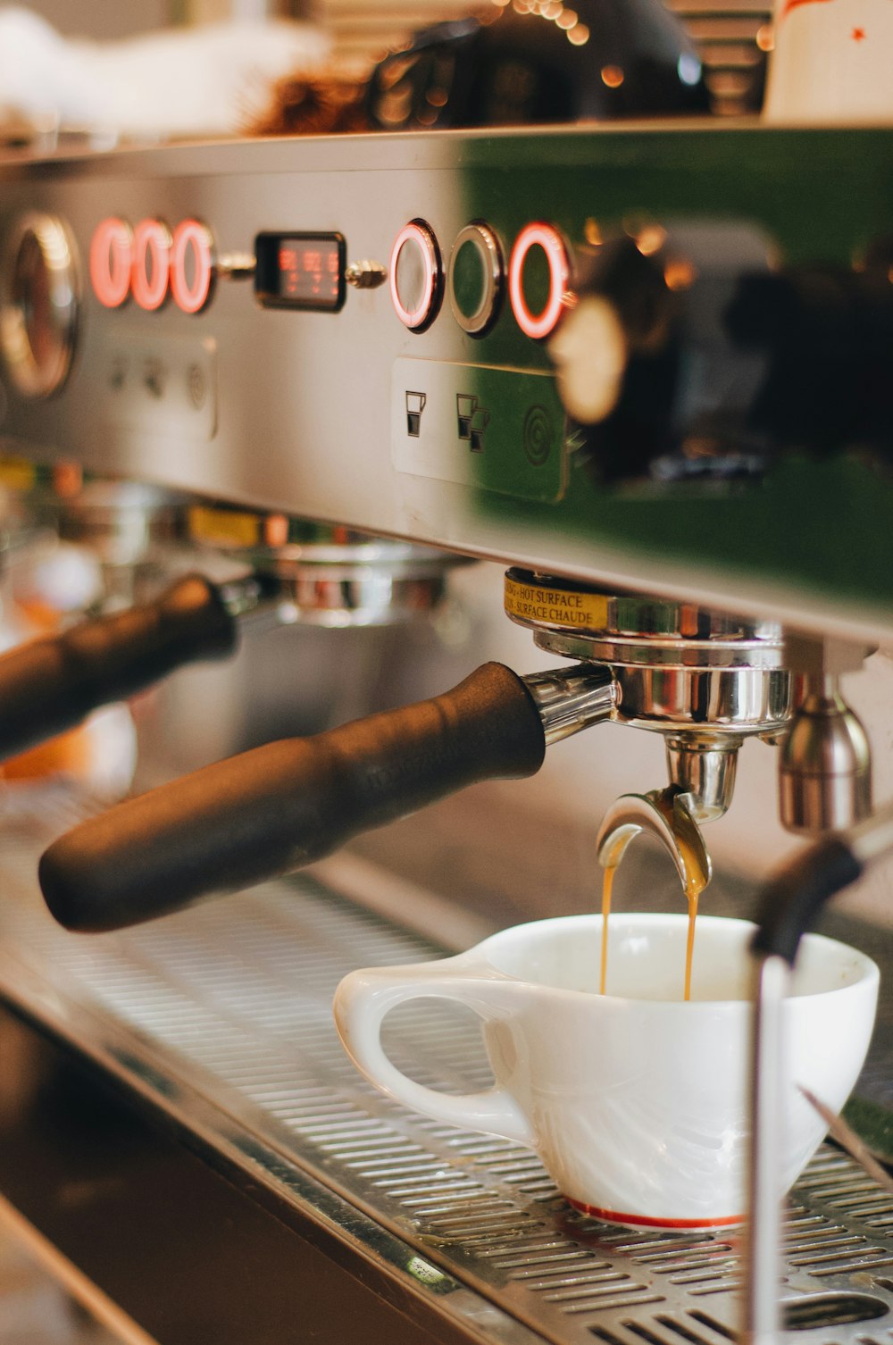 Taza de cerámica blanca en máquina de espresso plateada