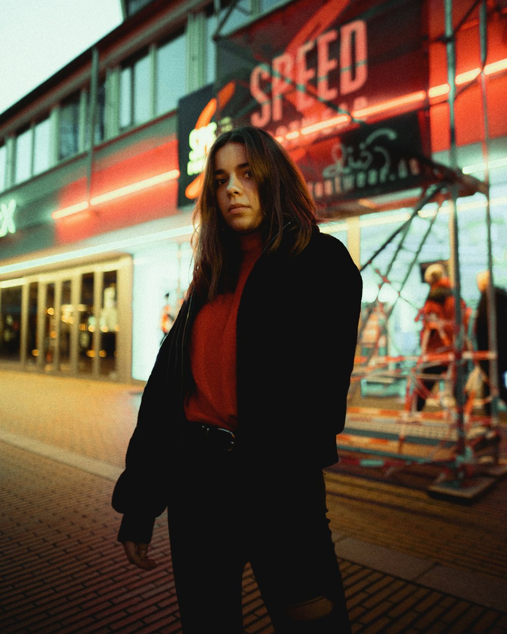woman in black long sleeve shirt standing near red and white neon signage during night time