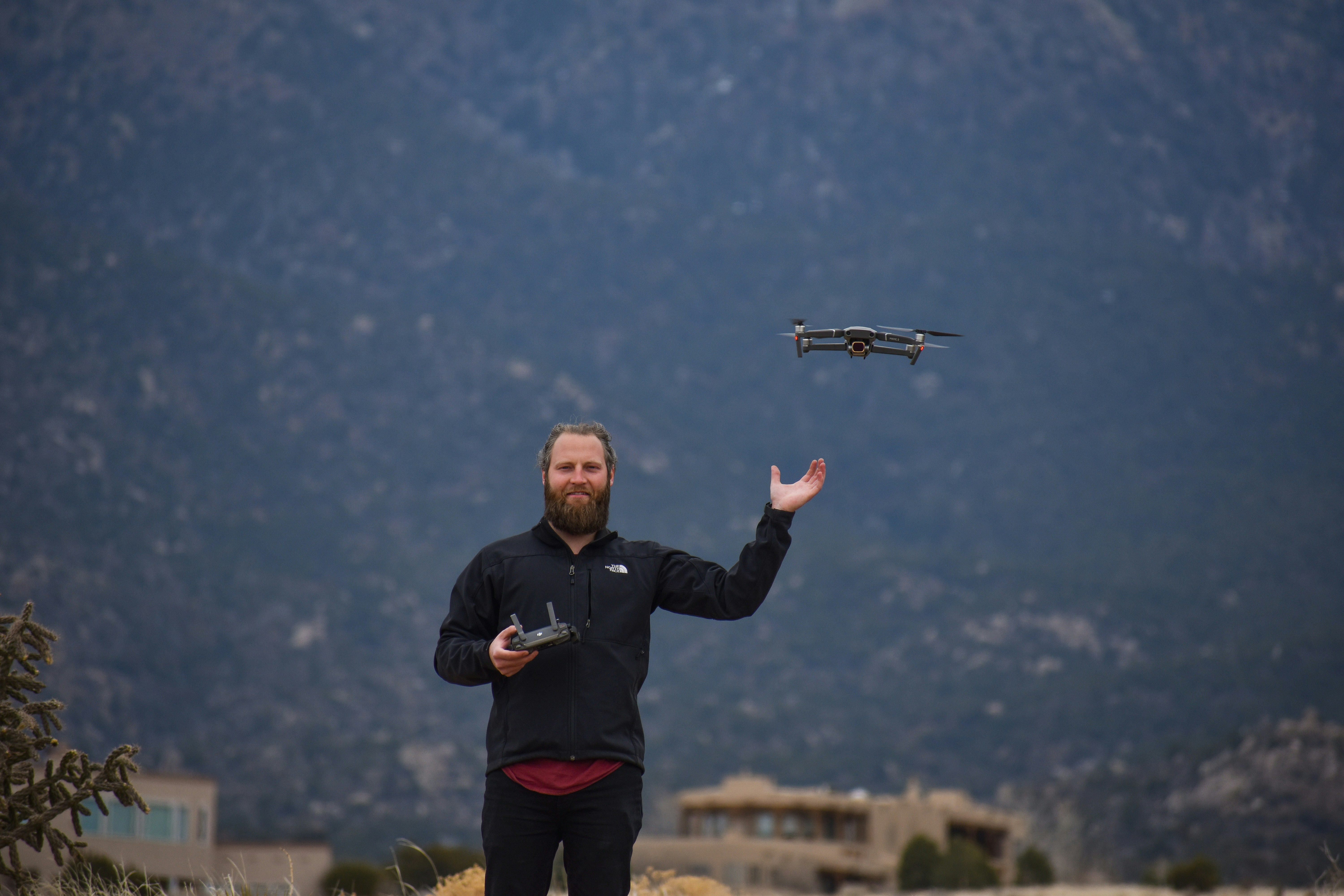 man in black jacket holding black and gray drone
