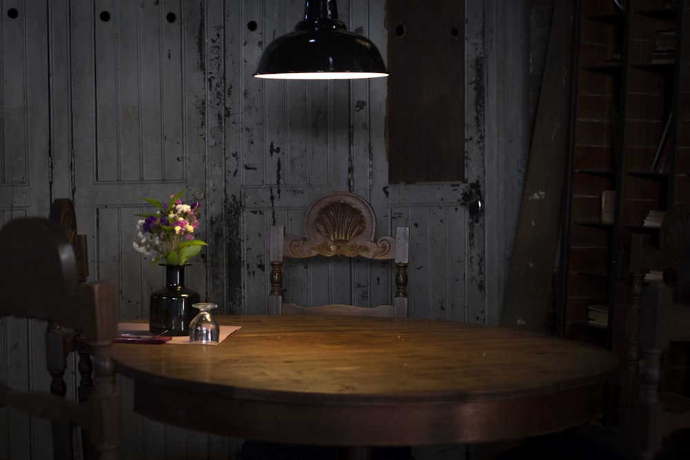 茶色の木製のテーブルの近くで点灯した黒いペンダントランプ