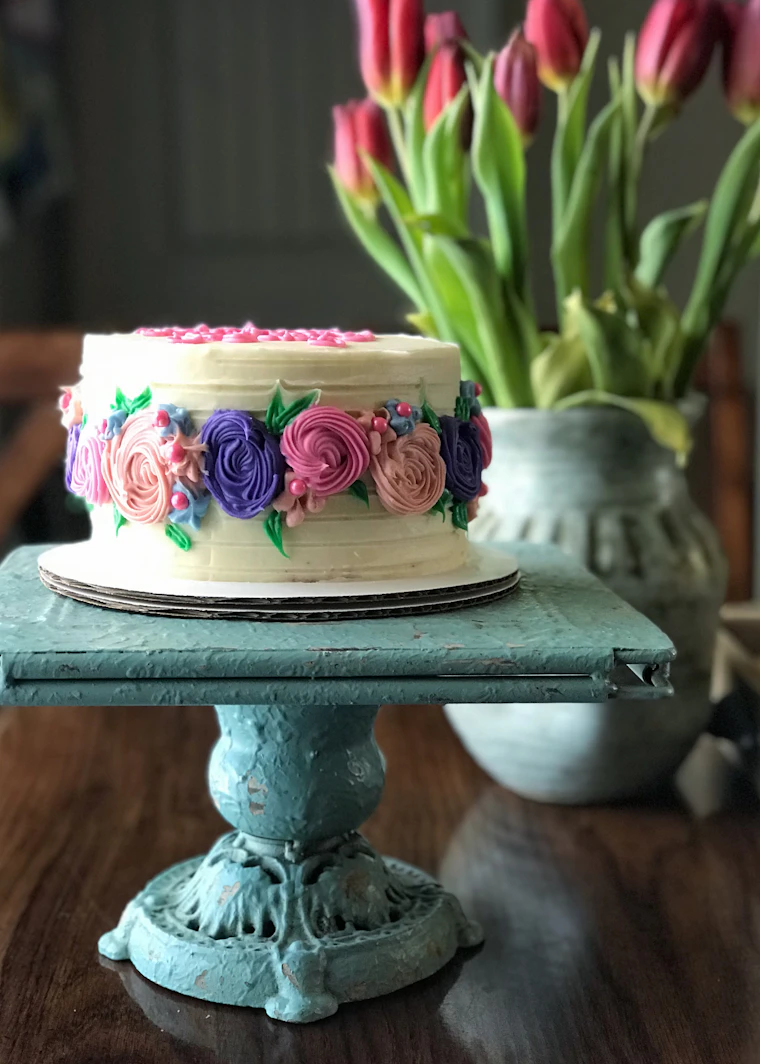 Pink and white floral birthday cake on a black cake stand