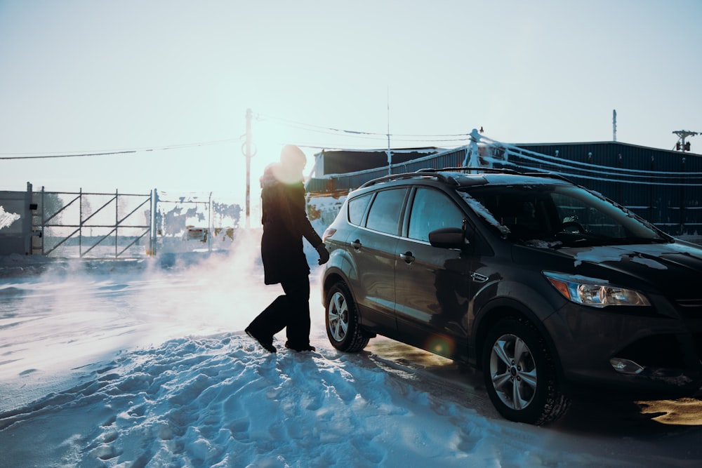 man in black jacket standing beside black suv during daytime