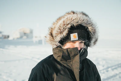 Model wearing a hoodie with winter resilience motifs standing against a snowy Minnesota backdrop.