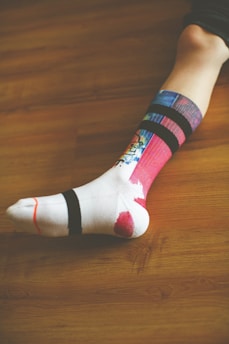 person wearing white green and pink sock