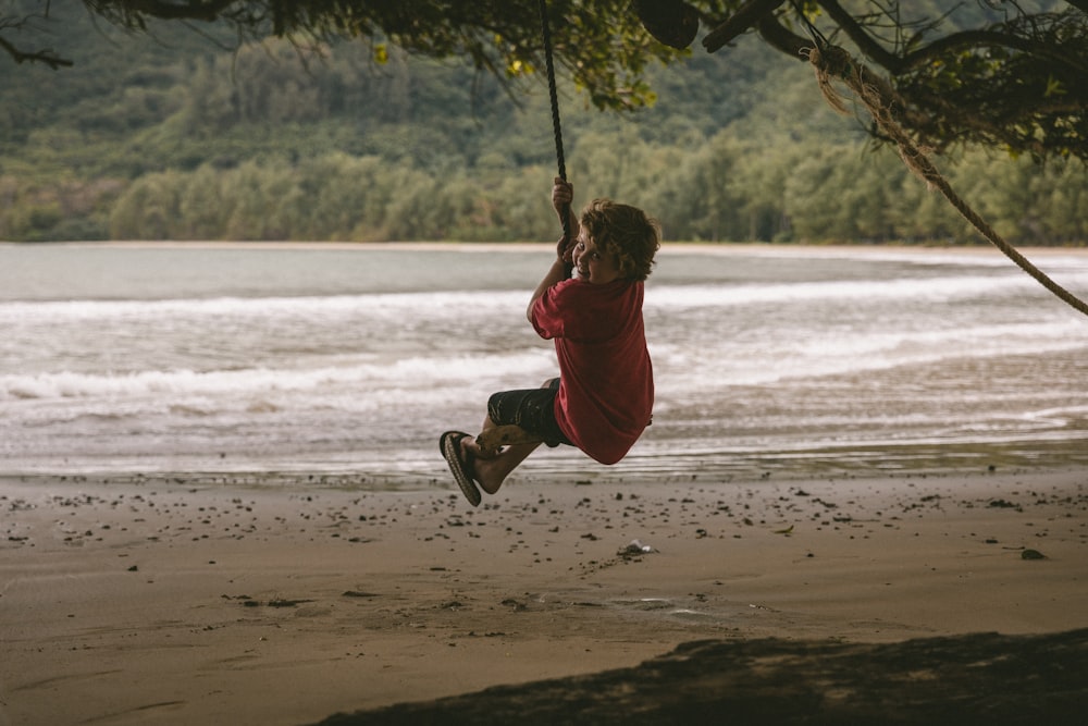 boy in red hoodie sitting on swing during daytime