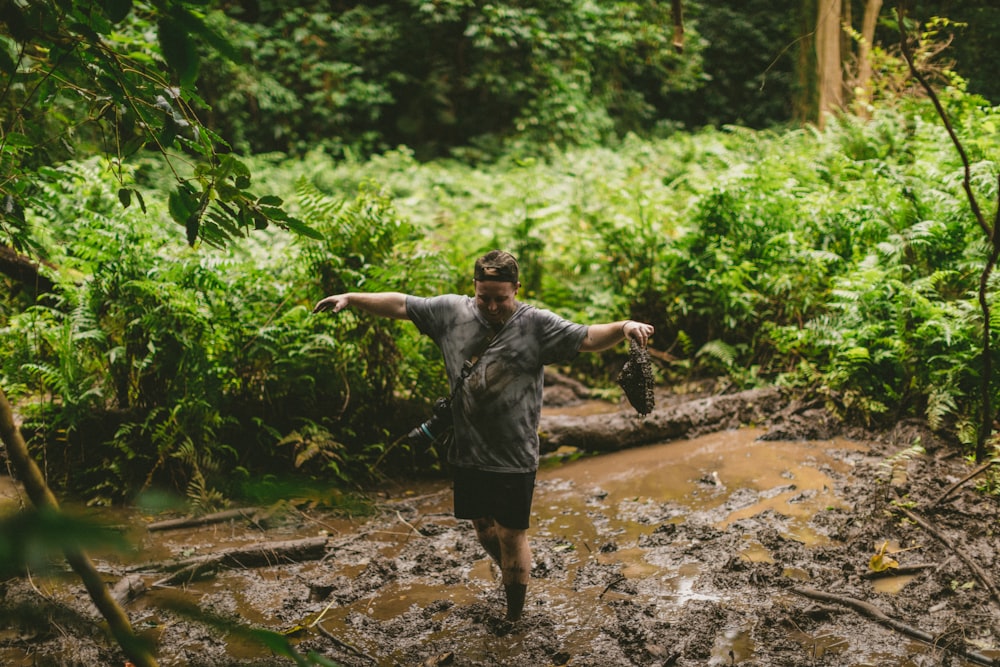 man in grey shirt and black shorts standing on dirt road