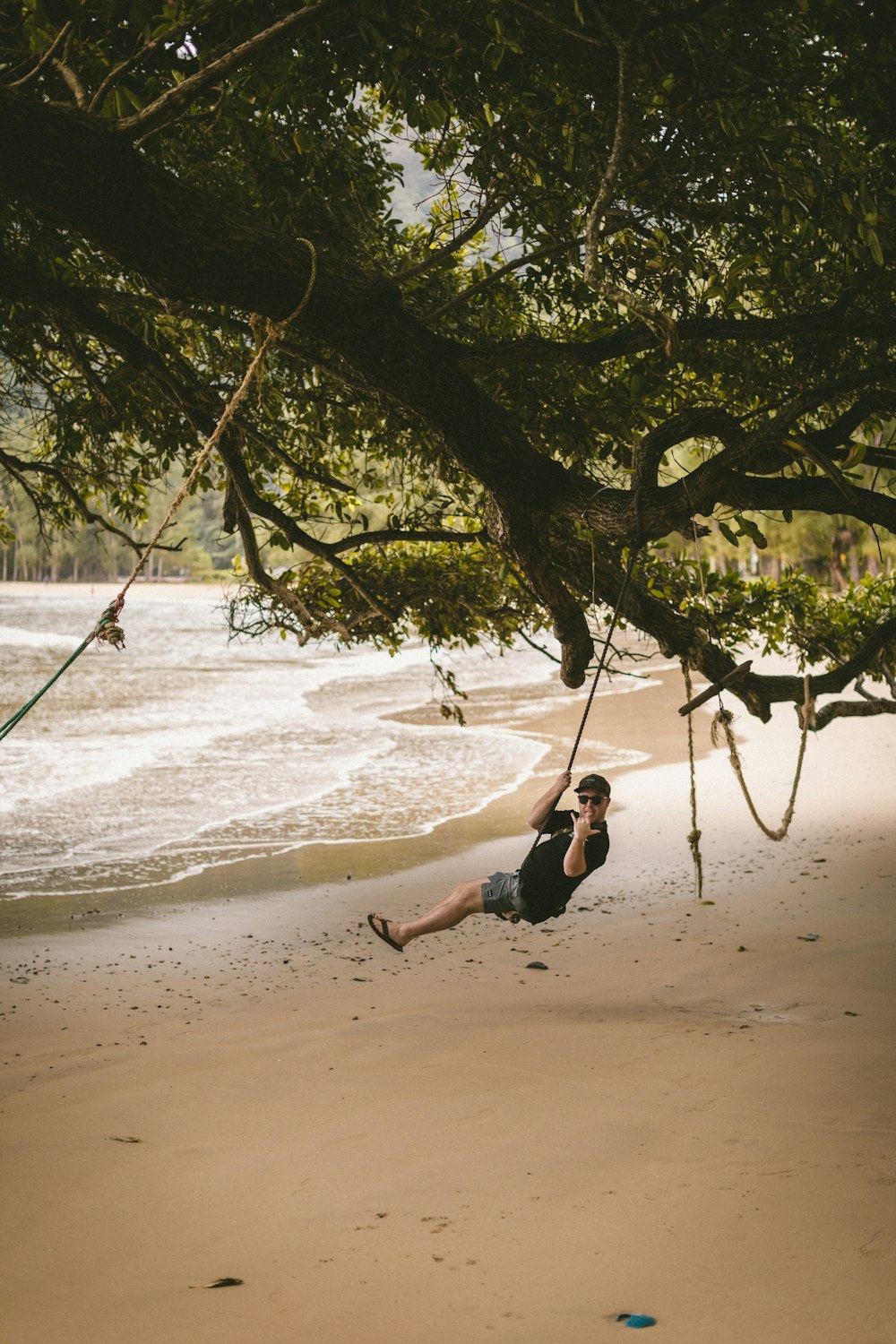 woman in black tank top and black pants doing yoga on beach shore during daytime