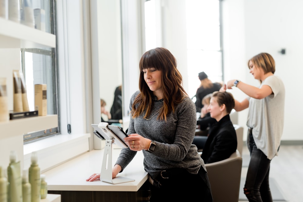 Femme en pull gris tenant une tablette