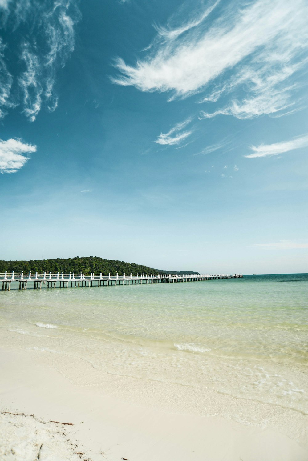 white wooden dock on sea under blue sky during daytime