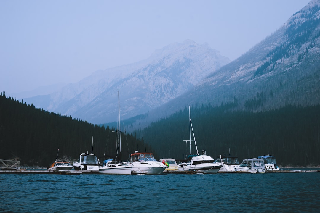 white and red boat on body of water near mountain during daytime