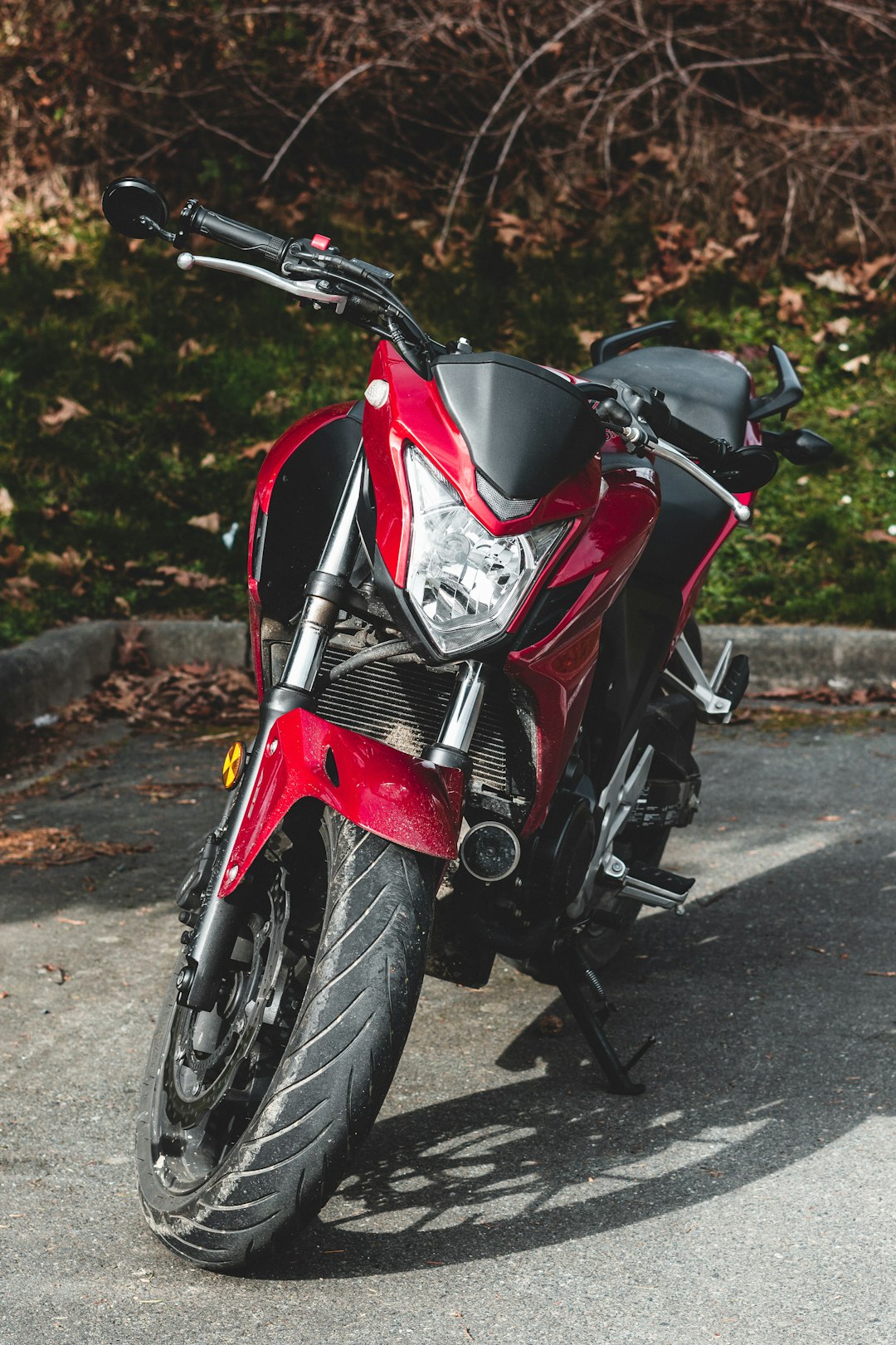 red and black sports bike parked on gray concrete road during daytime