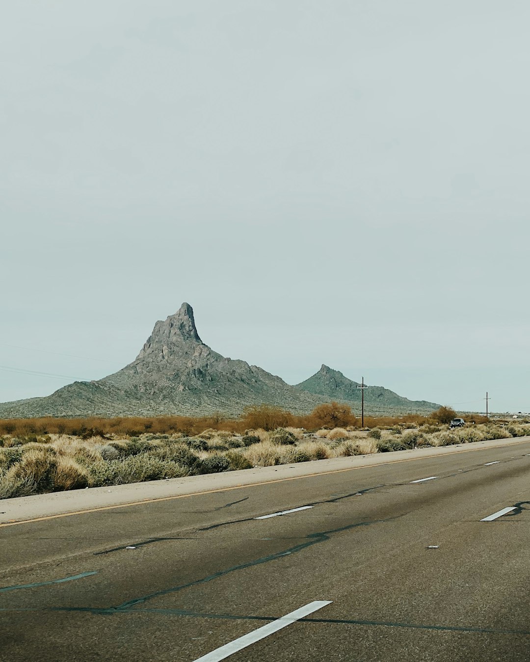 gray asphalt road near brown mountain during daytime