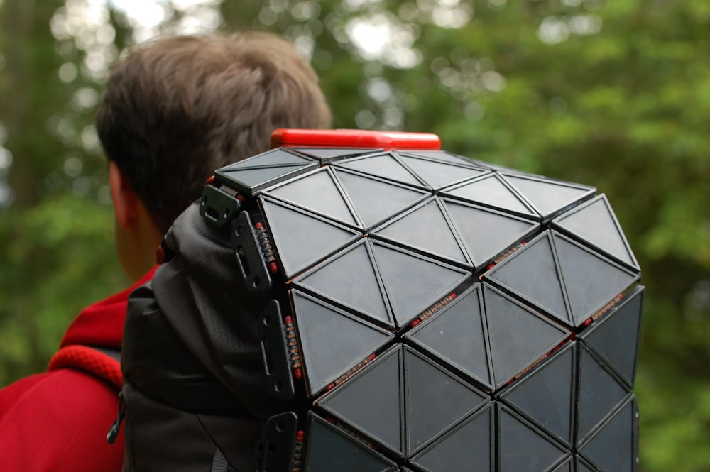 person in black leather jacket holding black and red square box