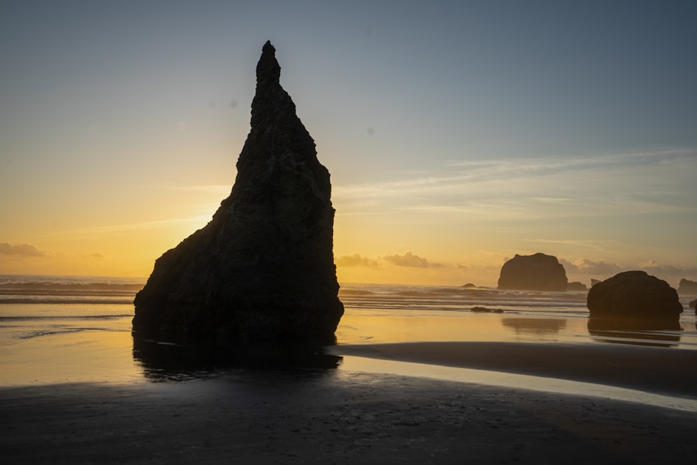 silhouette of rock formation on beach during sunset