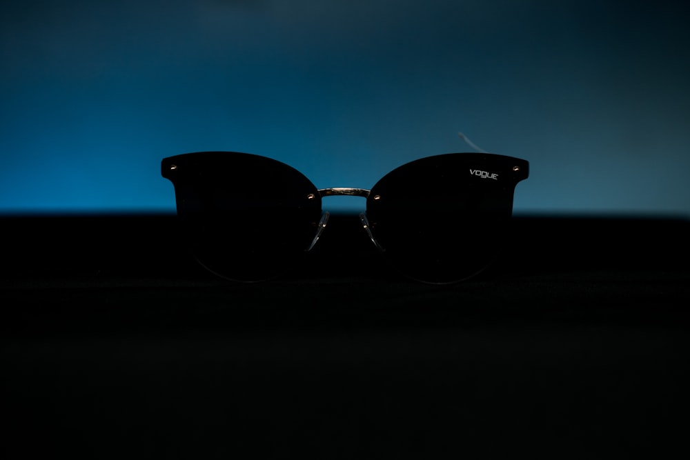black framed sunglasses on black surface