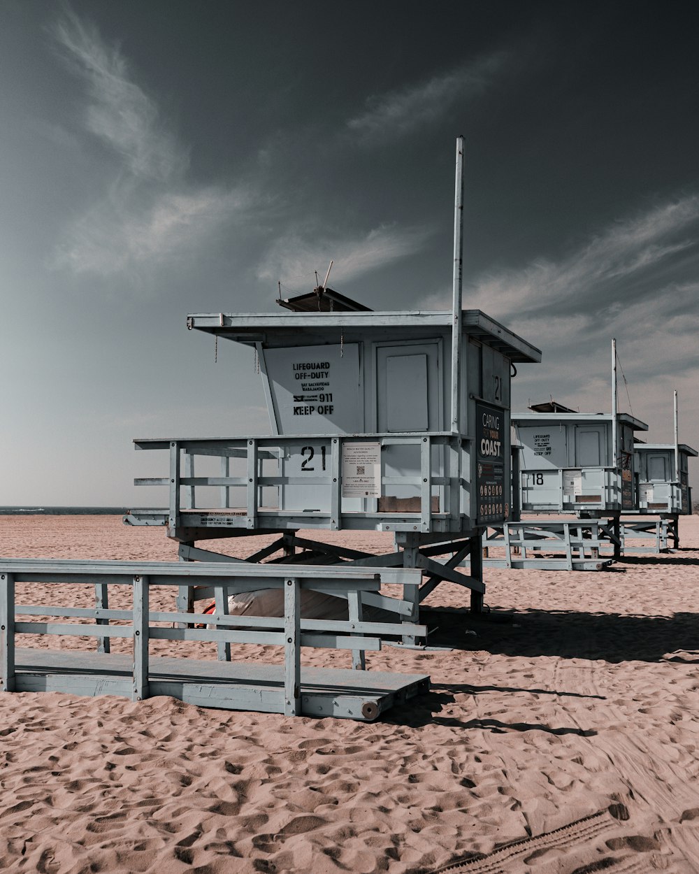 white and brown wooden lifeguard house on brown sand beach during daytime