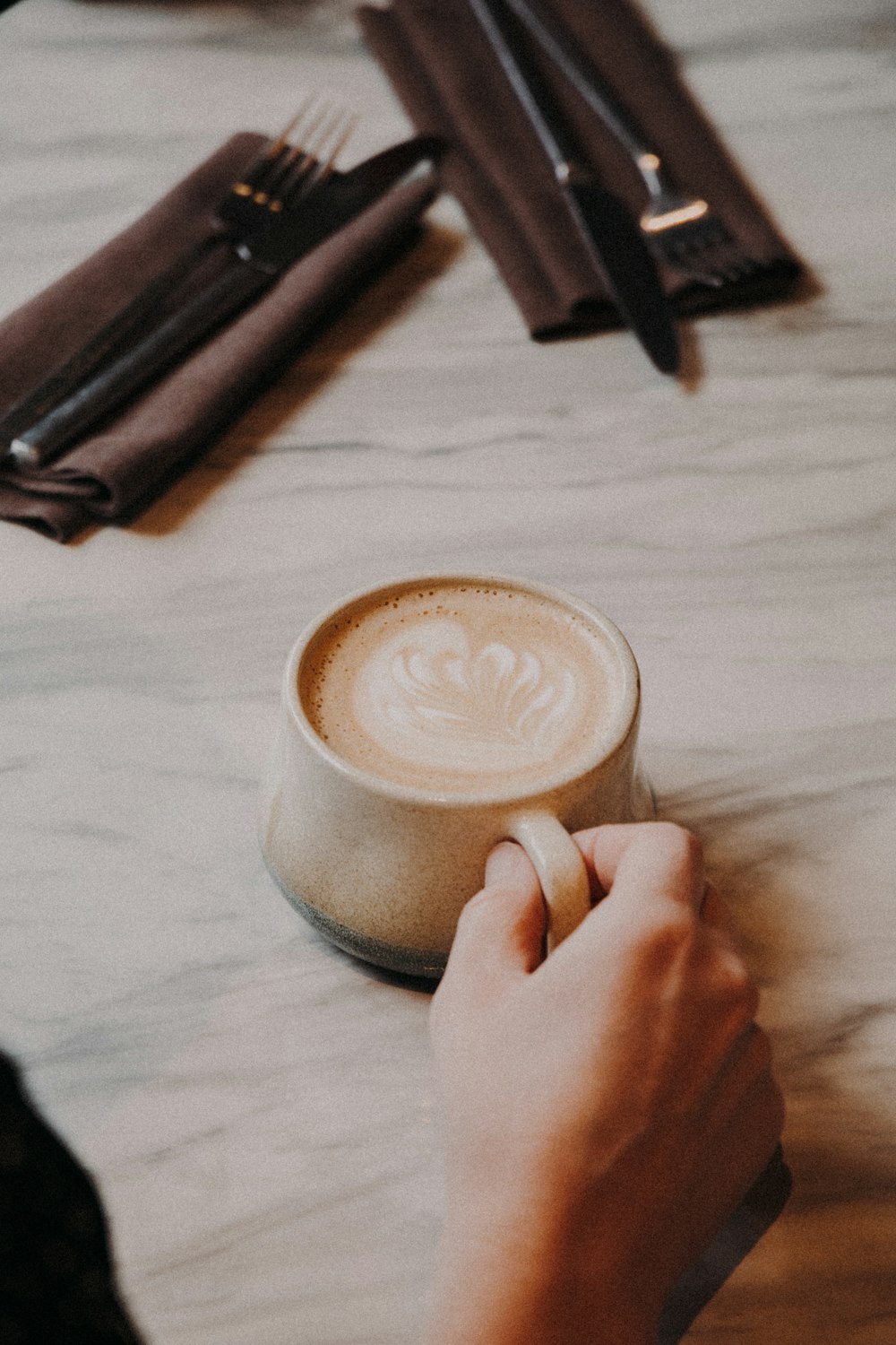 persona sosteniendo una taza de cerámica blanca con café