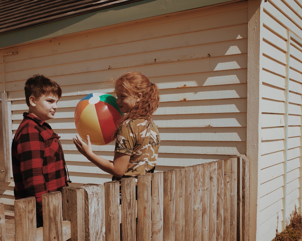 boy in brown jacket holding red yellow and blue balloons