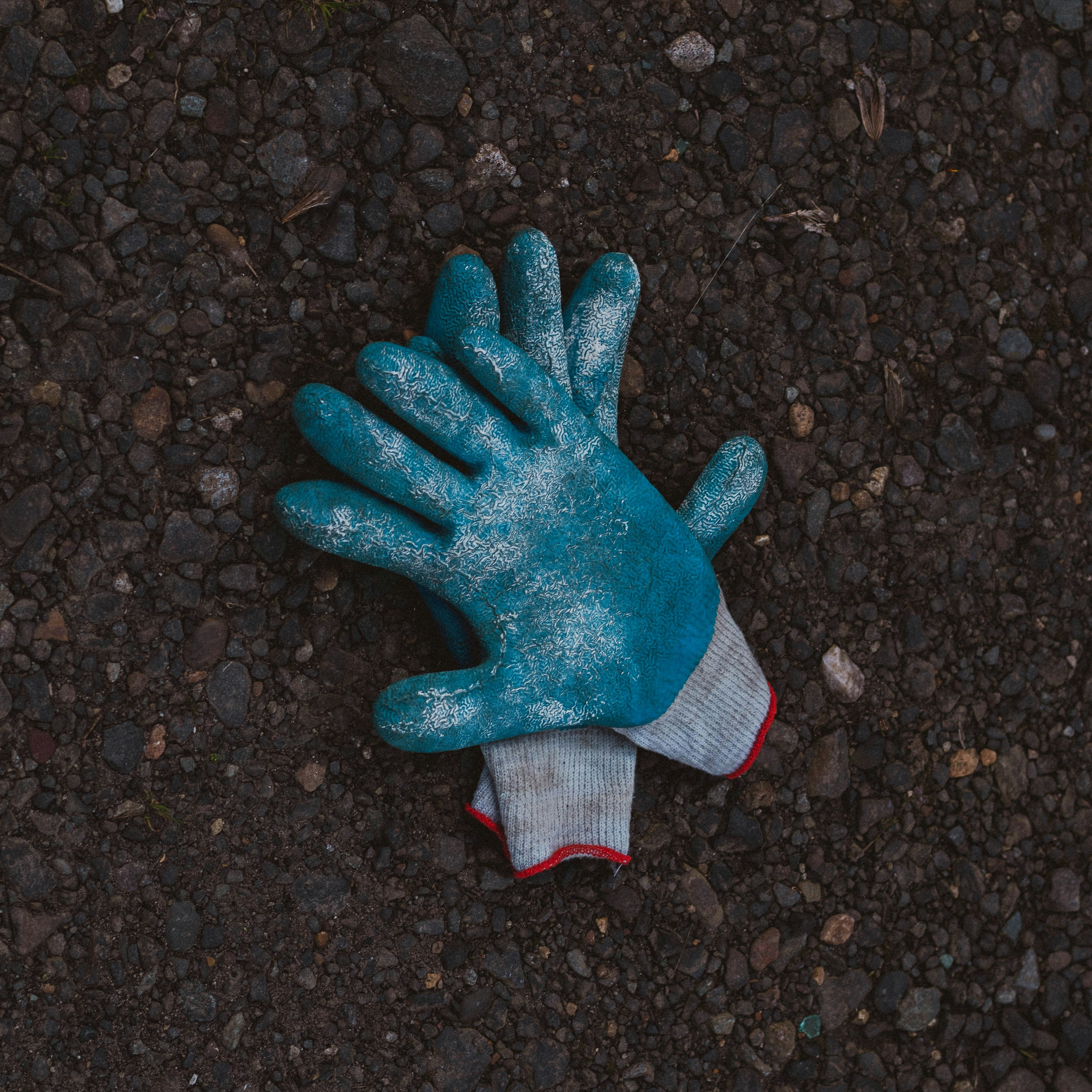 Guantes azules y grises sobre tierra negra