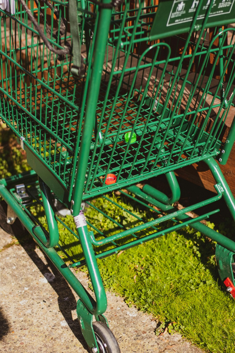 green metal shopping cart on green grass field during daytime