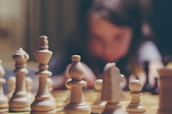 Close-up of a person analyzing a complex chessboard with intense focus.