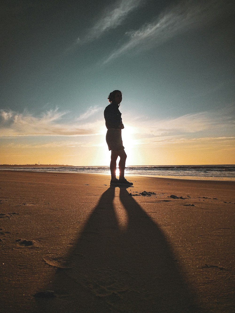 silhouette of man standing on beach during sunset