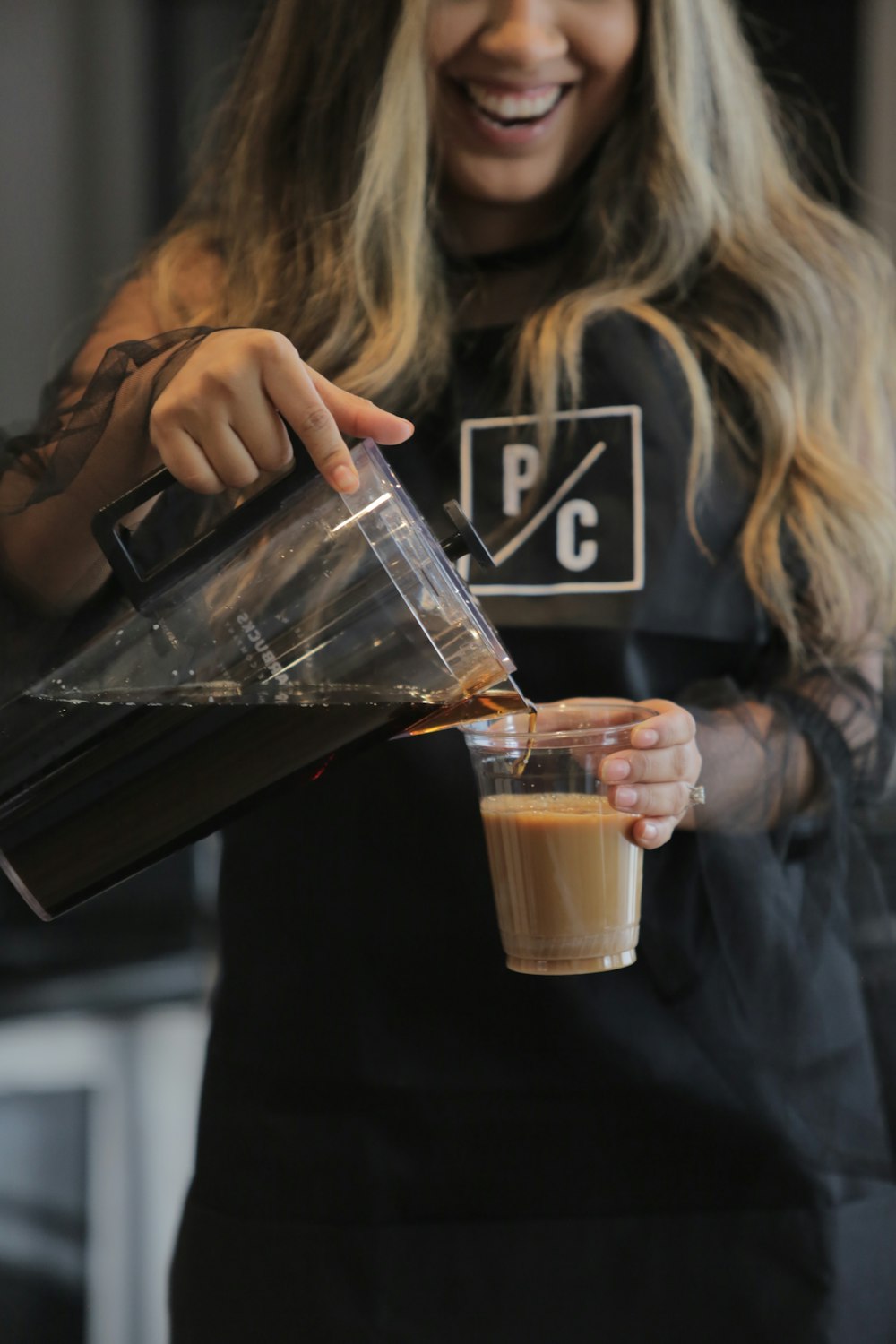 woman holding clear plastic cup with brown liquid