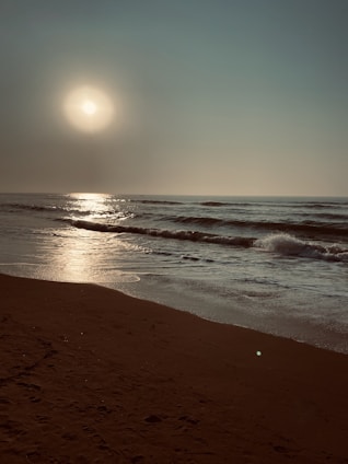 sea waves crashing on shore during sunset