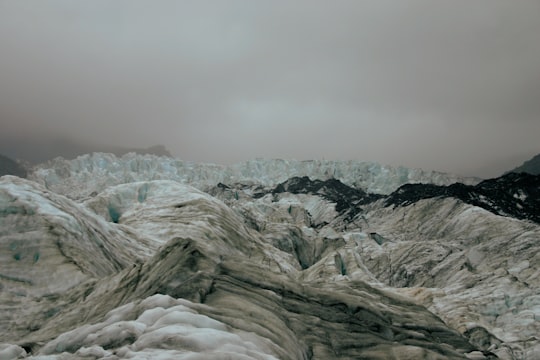 gray rocky mountain under gray sky in Fox Glacier New Zealand