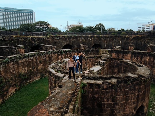 man in blue shirt standing on brown concrete stairs during daytime in Baluarte de San Diego Philippines