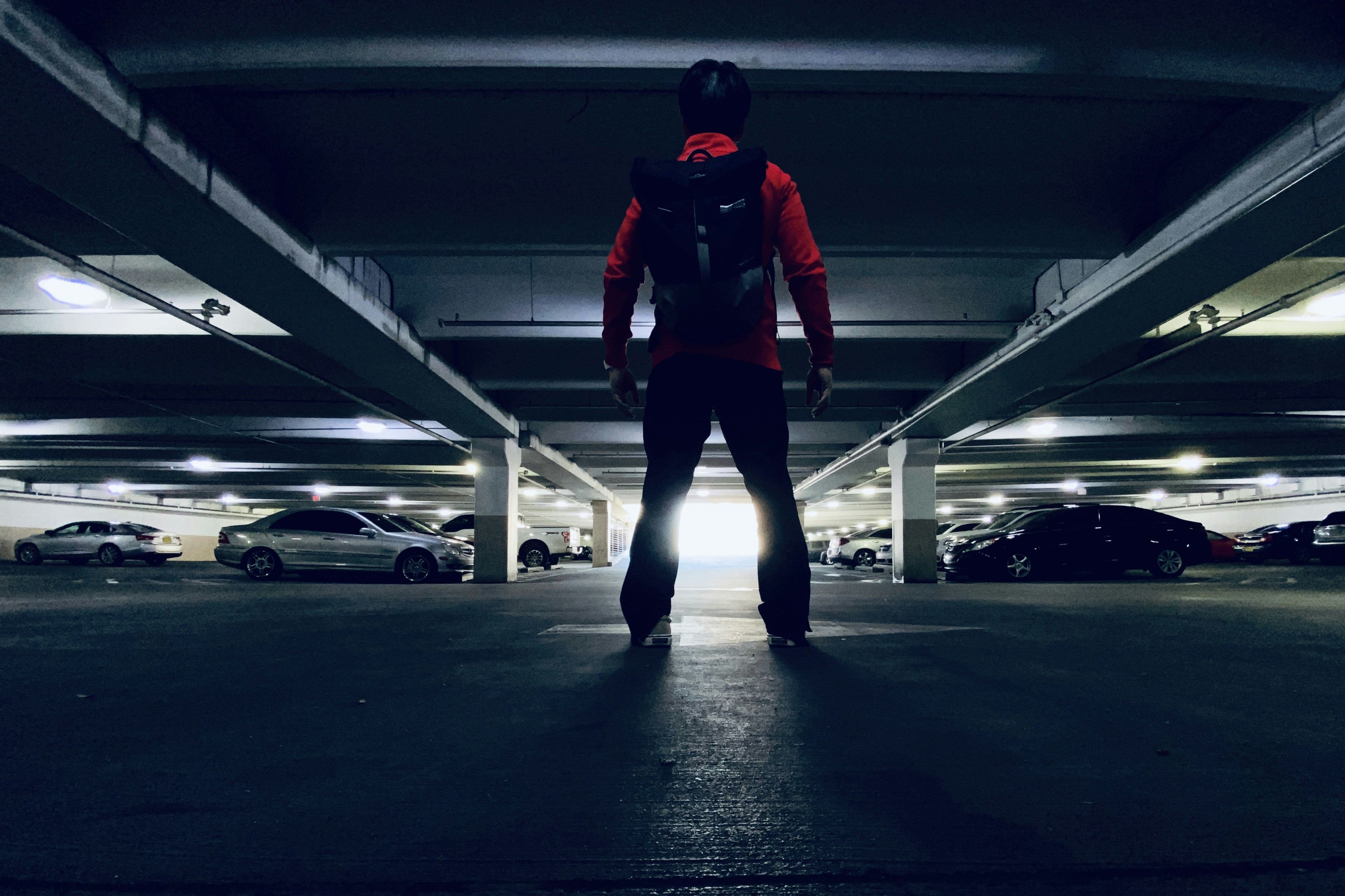 man in red and black jacket and black pants standing on black floor